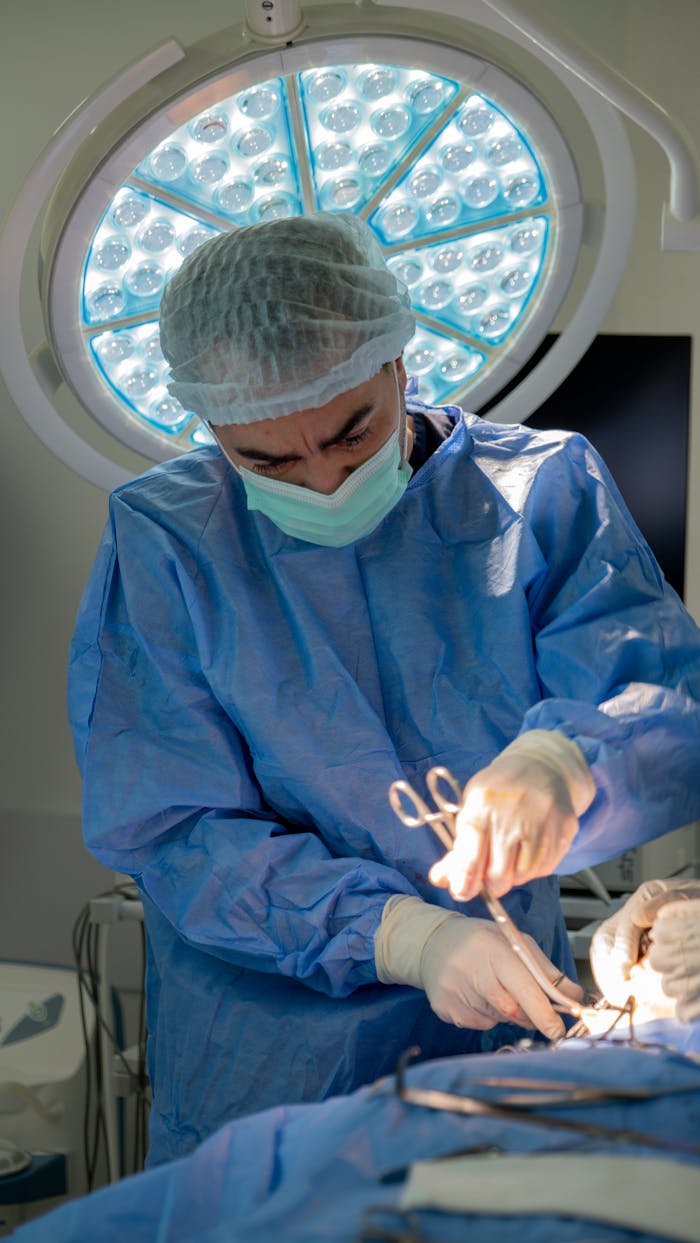 Surgeon in blue scrubs conducting a procedure under sterile conditions with surgical tools.