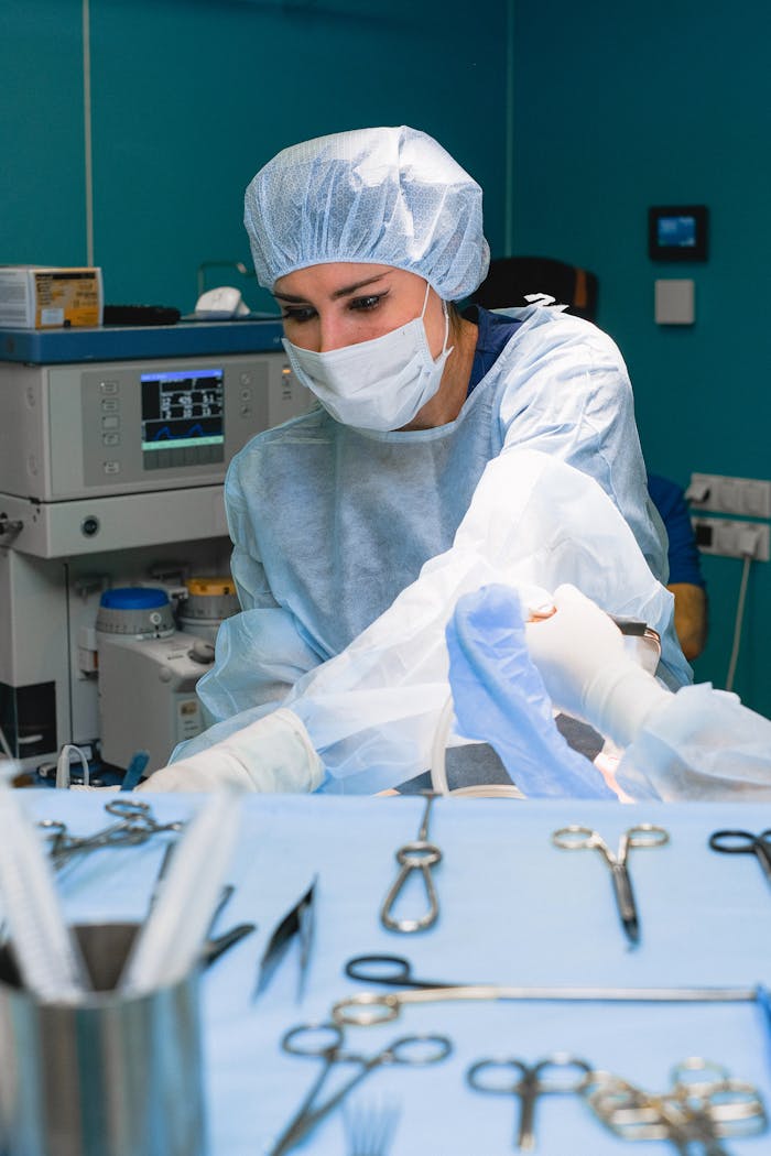 services-04 A female surgeon focuses on a procedure, surrounded by surgical tools in a hospital operating room.